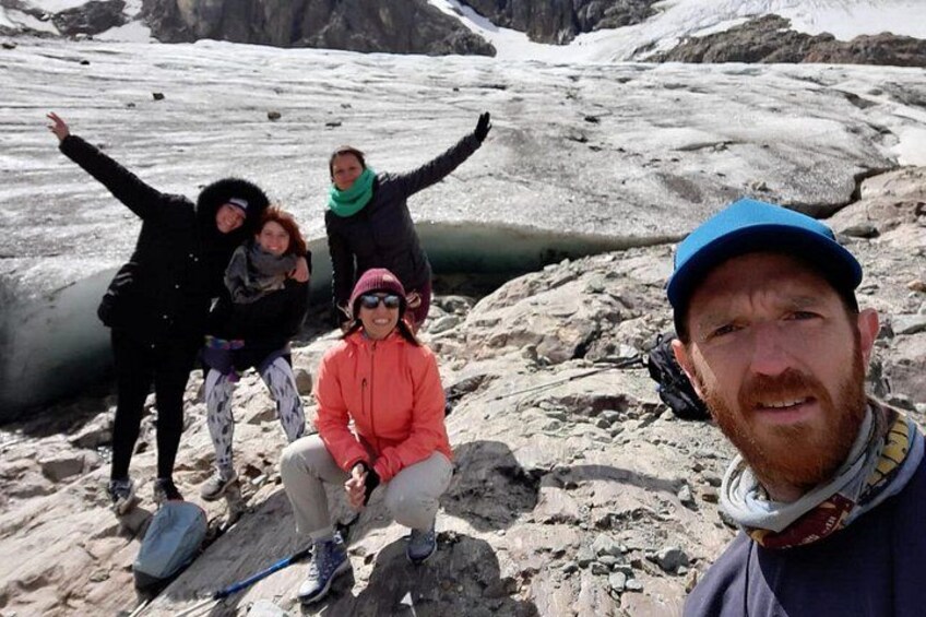 A group of people on a glacier with snow and ice in the background. 3