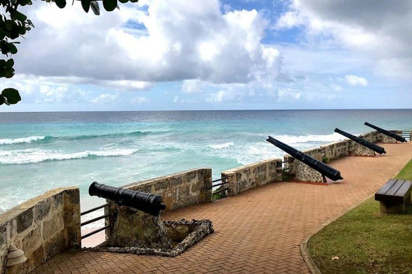 Une promenade en bord de mer, avec des canons, des vagues et un ciel nuageux. 1