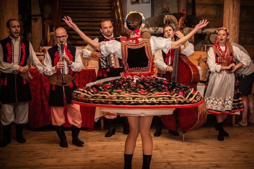 Eine Gruppe von Menschen in traditioneller Kleidung tanzt um einen geschmückten Tisch. 1