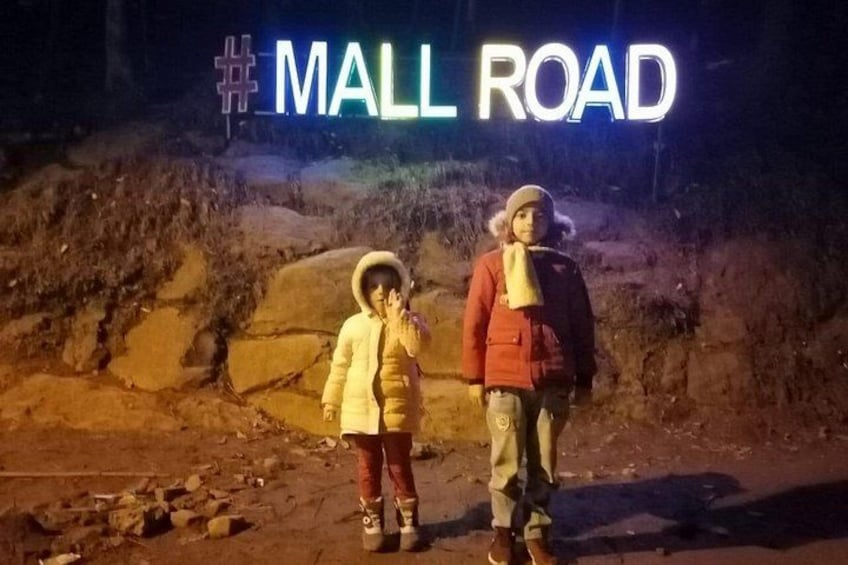 Deux personnes se tiennent devant un panneau indiquant « MALL ROAD » la nuit. 5