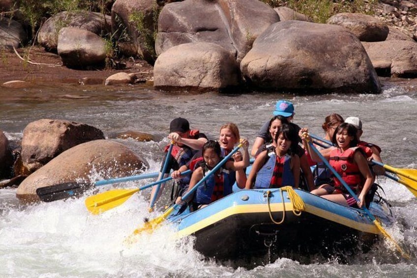 A group of people rafting on a river surrounded by large rocks. 1