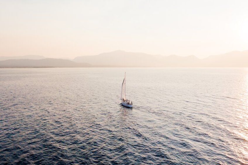 Un velero en aguas tranquilas con montañas a lo lejos. 4