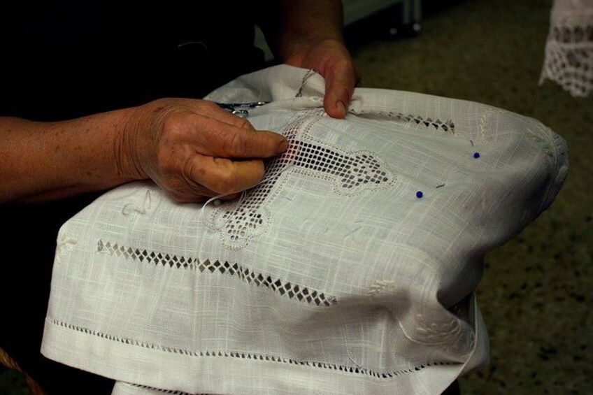 Manos trabajando sobre una tela blanca con diseños de encaje. 4