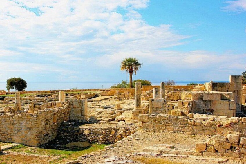 Ruinas antiguas con columnas y muros de piedra, una palmera y cielo despejado. 5
