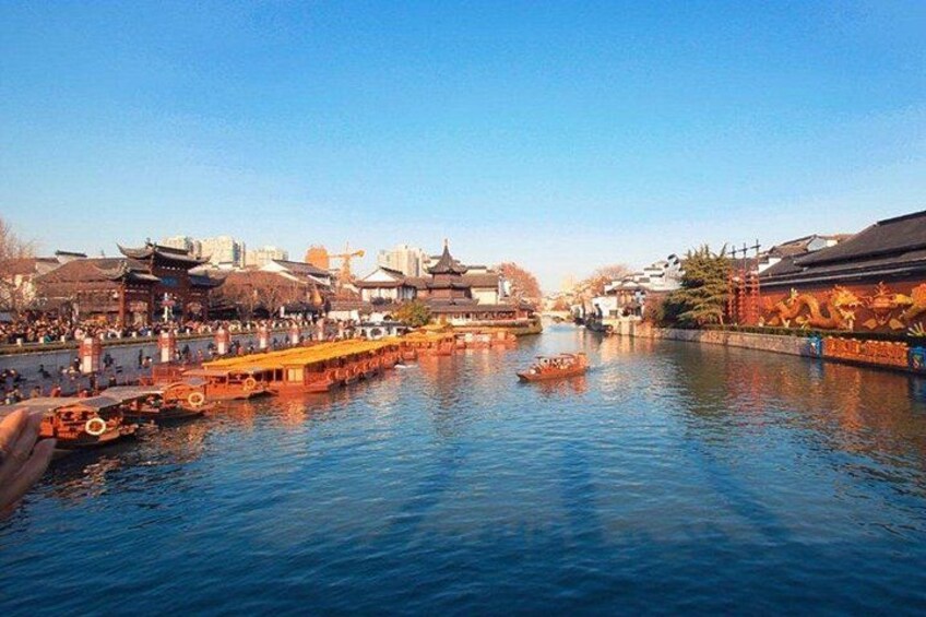 A river with traditional boats, buildings, and a clear sky. 1