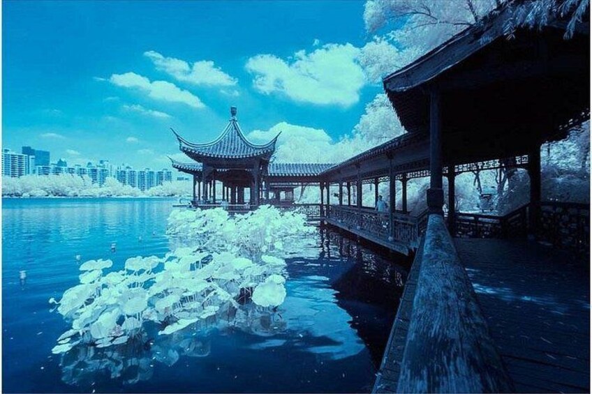 A traditional pavilion over a body of water, surrounded by snow-covered trees and a city skyline in the background. 3