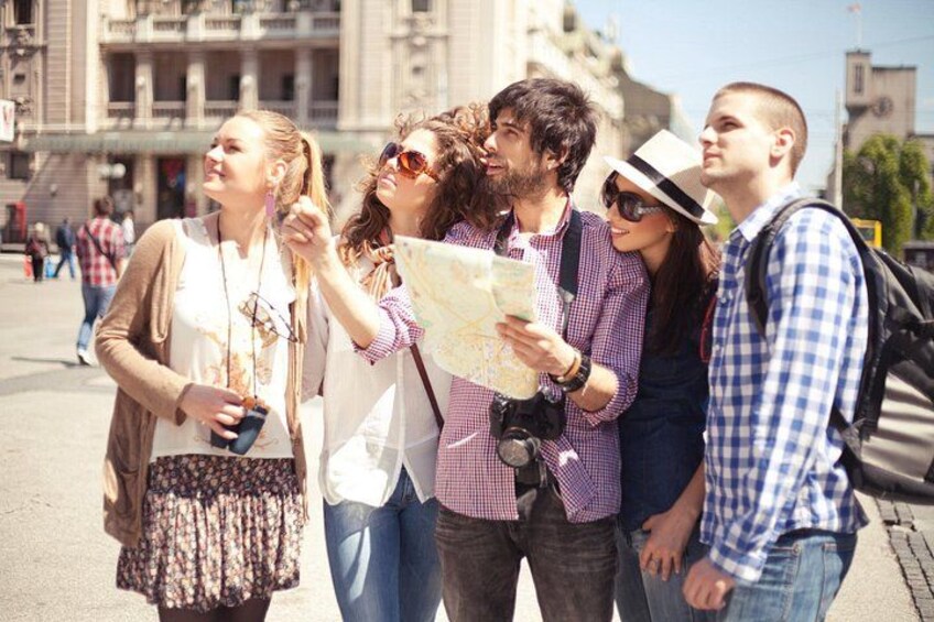 A group of people standing on a street, some holding maps. 2