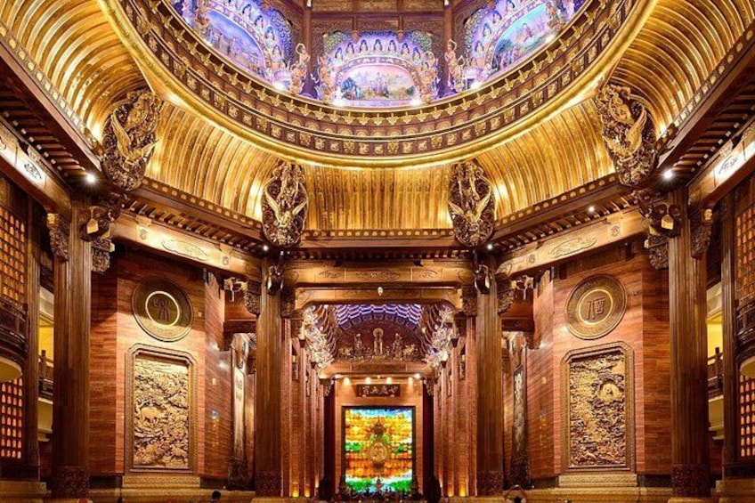 An ornate theater interior with a grand chandelier, detailed woodwork, and a stained glass window. 2