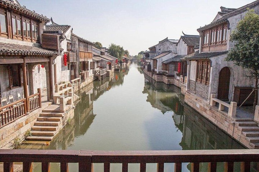A canal flanked by traditional buildings with wooden railings and steps leading down to the water. 4
