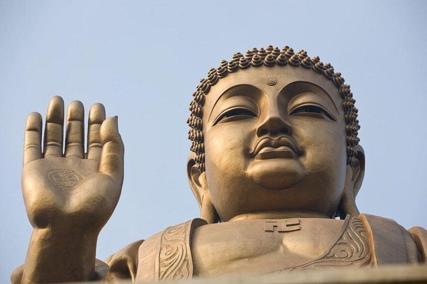 A large statue with a raised hand, intricate carvings, and a clear sky in the background. 3