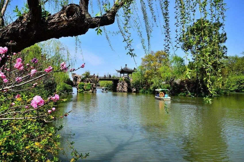 A calm river with a traditional boat, a bridge, and a pavilion. 3