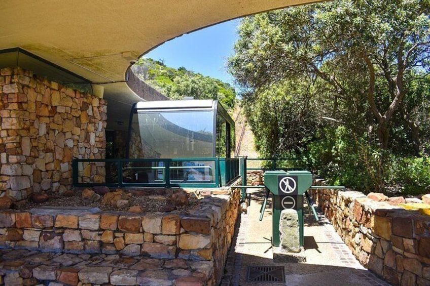 A stone wall, a covered area, and a green structure with a sign. 3