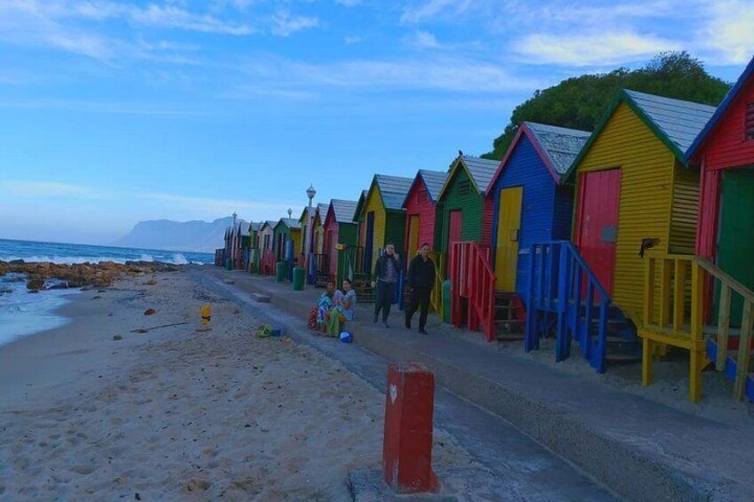 A row of colorful beach huts along a sandy beach with the ocean in the background. 2
