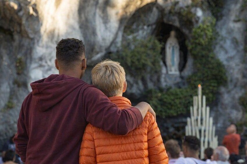 Two people embracing in front of a cave with a statue inside. 4