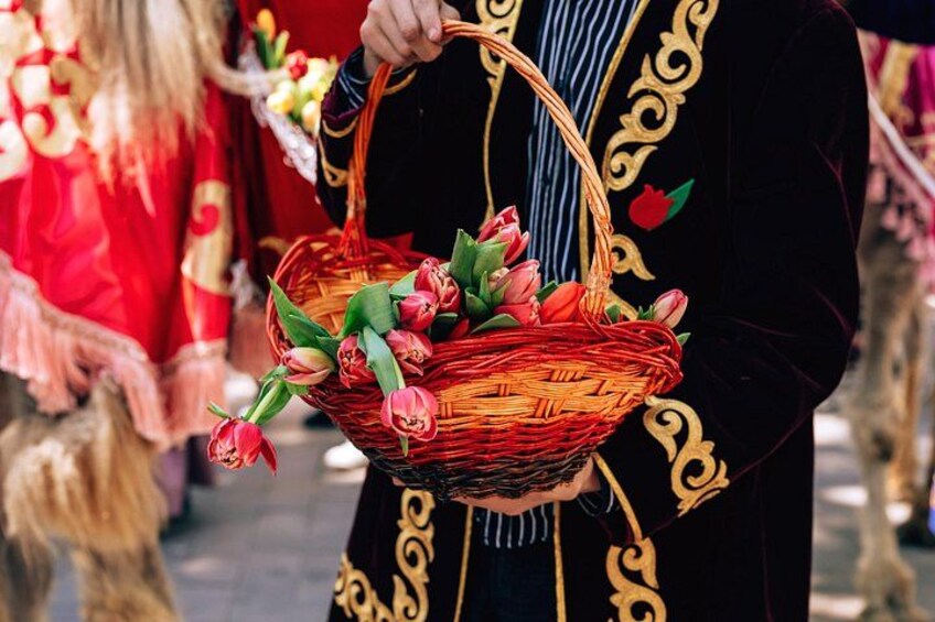 Eine Person hält einen Korbkopf mit roten Tulpen. 2