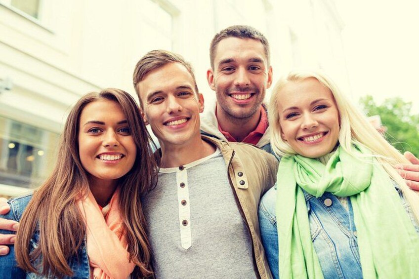 Four people standing close together in front of a building. 4