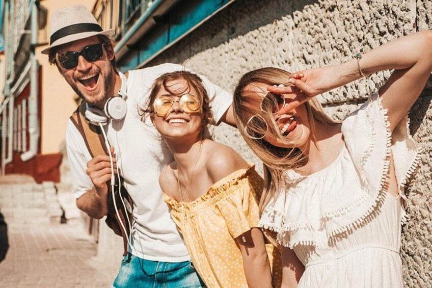 Three people standing in a street with a textured wall behind them. 3
