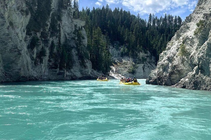 Un río de aguas turquesas cristalinas, rodeado de acantilados rocosos y un bosque denso. 1