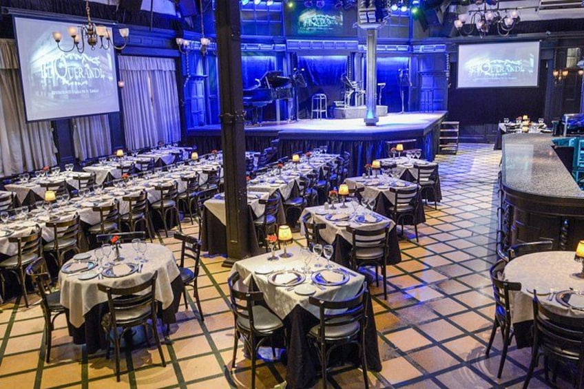 Une salle de banquet avec des tables rondes, des chaises, une scène et un espace bar. 2