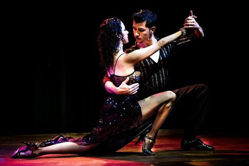 Un couple interprète une danse sur une scène dont le fond est sombre. 5