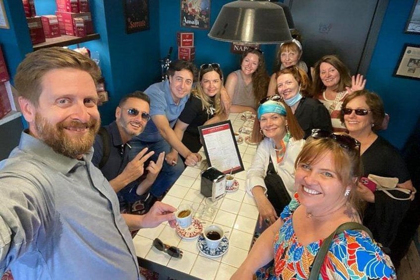 A group of people seated around a table in a cafe with a menu and a coffee cup visible. 2