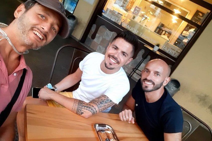 Three people sitting at a wooden table with a smartphone and a metal object on it. 5