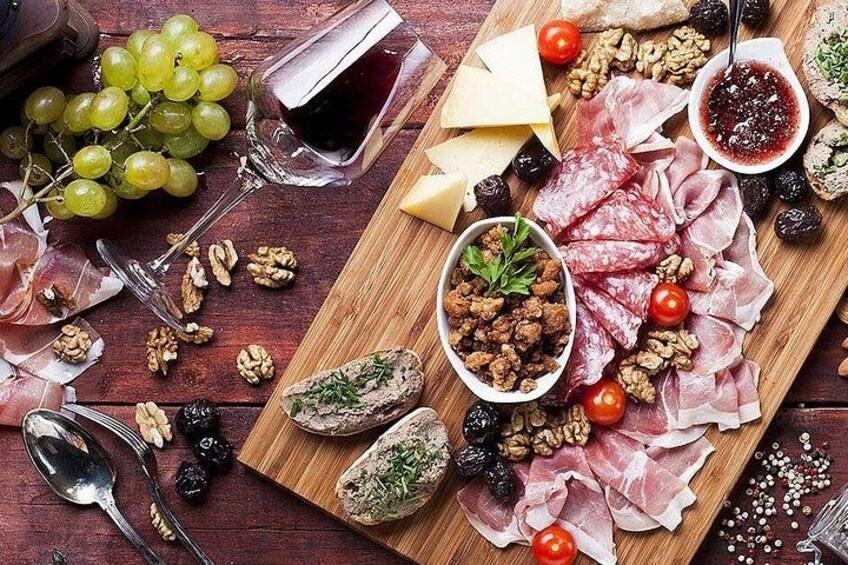 A charcuterie board with various meats, cheeses, grapes, nuts, and a bowl of nuts. 1