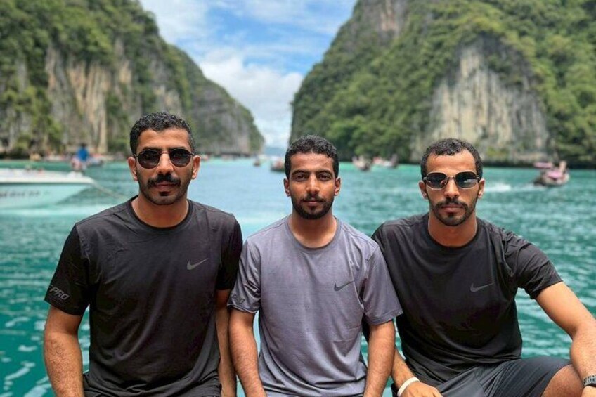 Drei Personen in einem Boot in einer Bucht mit Klippen. 3