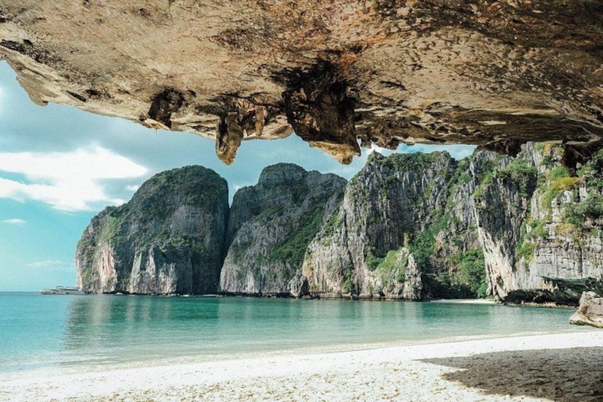 A beach with large limestone cliffs and calm turquoise waters. 3