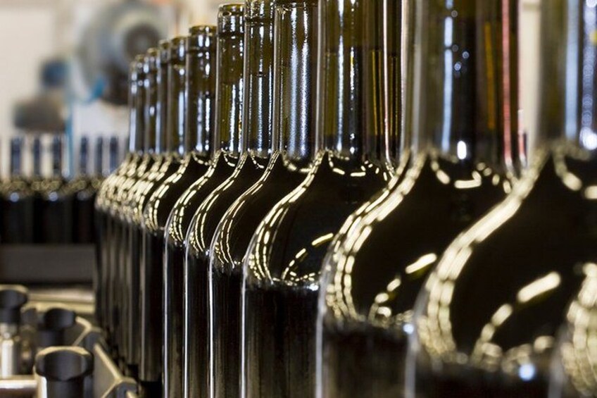 A row of clear glass bottles with metallic caps, likely in a storage or display setting. 5