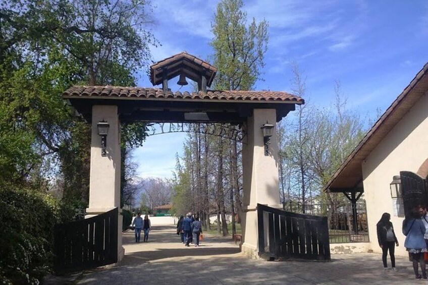 A gated entrance with a tiled roof, surrounded by trees and a clear sky. 4