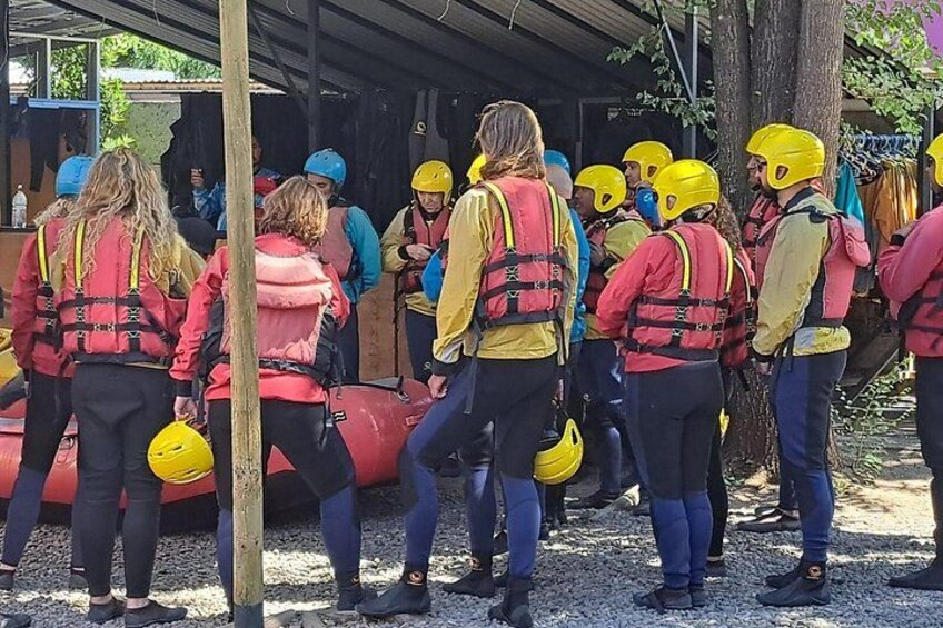 Een groep mensen in rode en gele vesten met helmen, staand bij een rode opblaasbare boot. 2