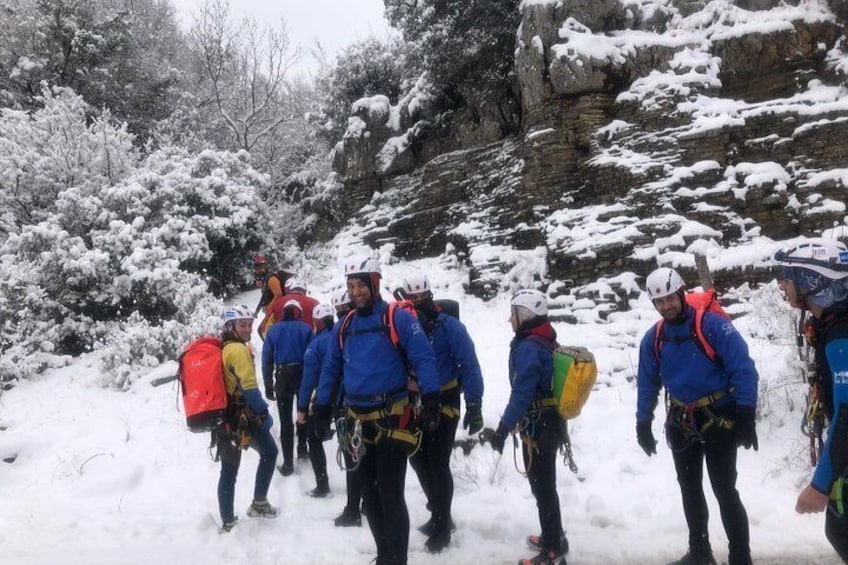 Een groep mensen in blauwe jassen en helmen loopt over een besneeuwd pad. 5