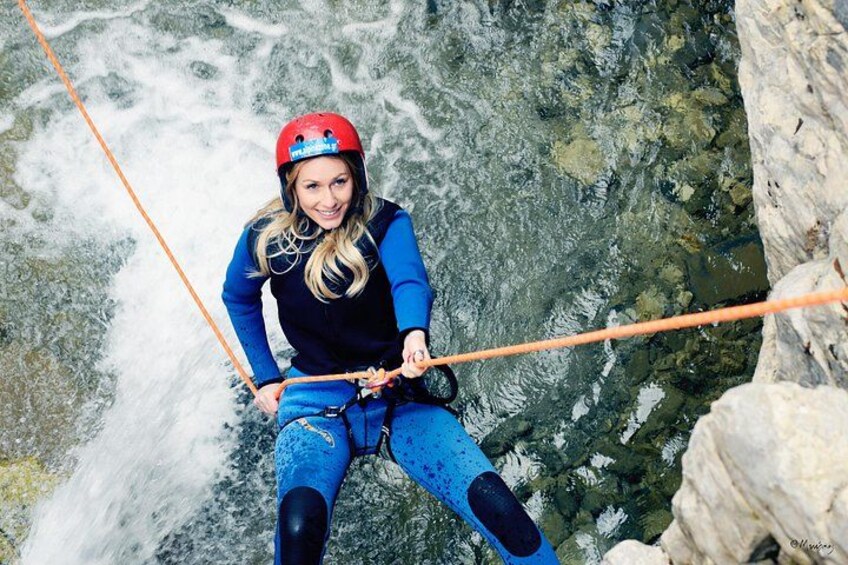 A person rappelling down a rocky cliff with a rope. 2