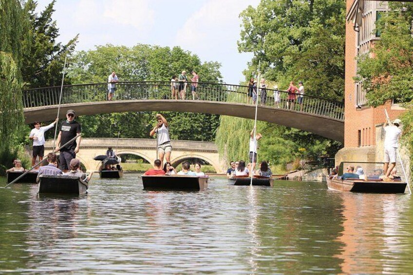 A river with people on boats, a bridge, and trees in the background. 3