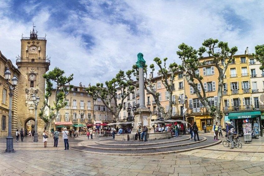 Une place publique avec un beffroi, une fontaine et des bâtiments qui l’entourent. 3