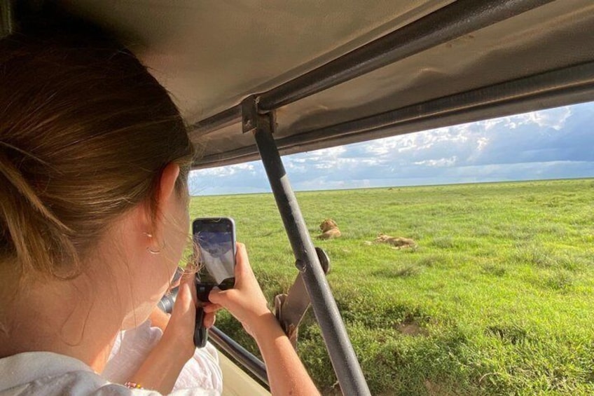 A person taking a photo of a grassy field through a vehicle window. 1