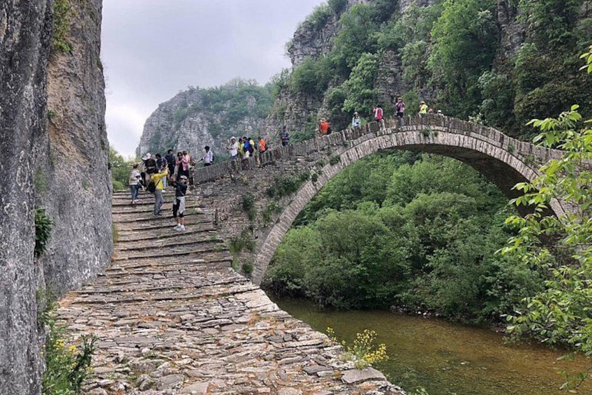 A stone bridge over a river with people walking on it. 1