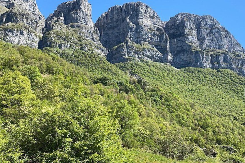 A mountainous landscape with dense green vegetation and rocky cliffs. 2