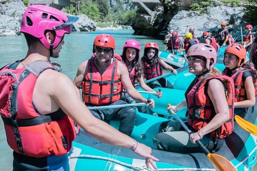 A group of people in inflatable rafts on a river, wearing life jackets and helmets. 4