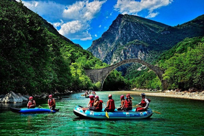 People kayaking on a river with a bridge in the background. 3