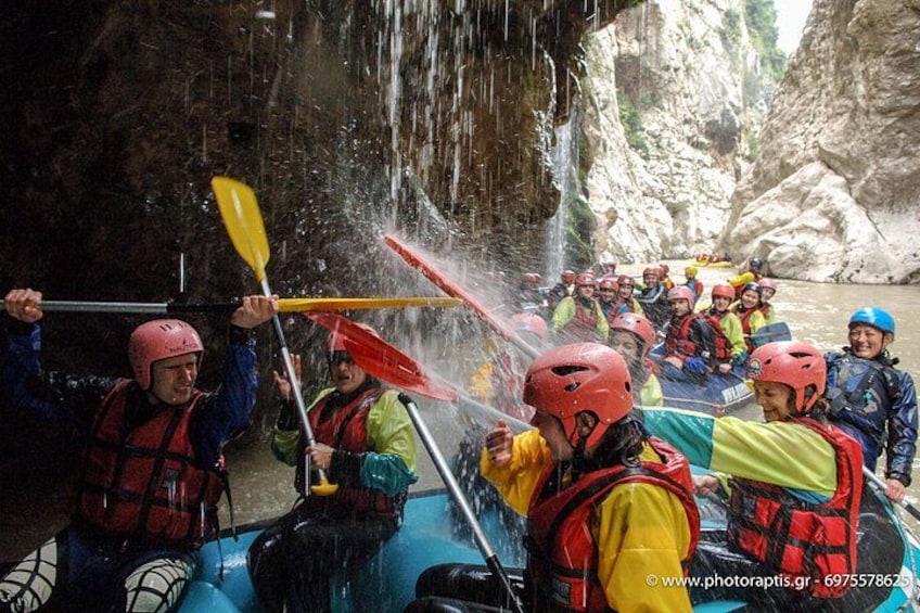 A group of people in a raft navigating through a narrow, rocky canyon with water cascading down from above. 5