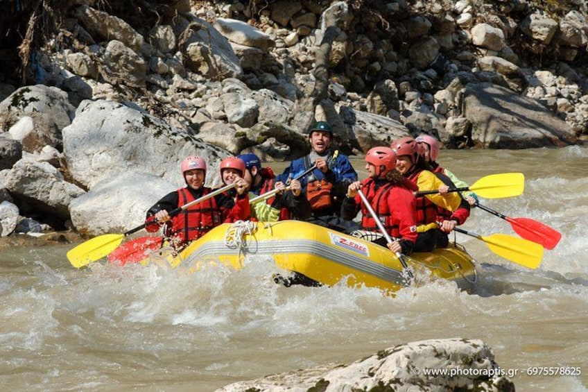 A group of people in a yellow raft navigating a river with rocks and boulders. 3