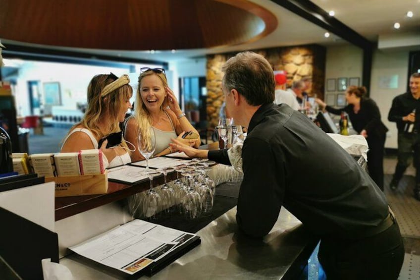 A restaurant interior with a bar area, people dining, and a waiter attending to customers. 4