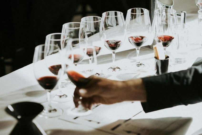 A table with multiple wine glasses, some filled with red wine. 5