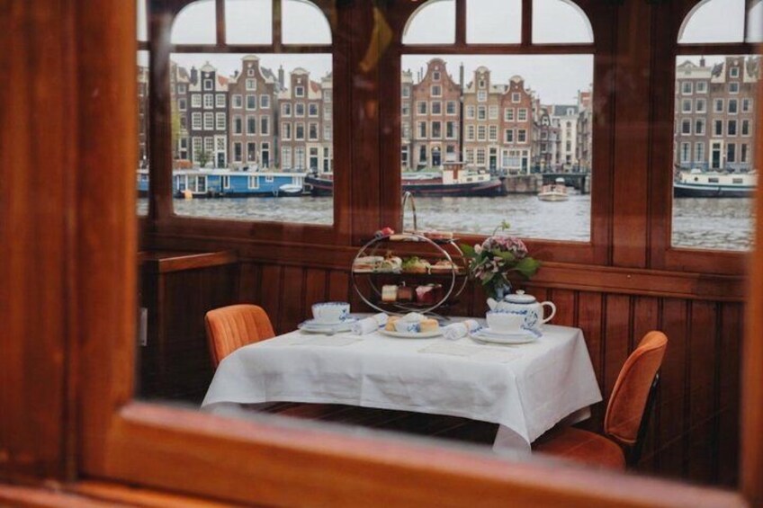 Ett dukat bord för eftermiddagste med utsikt över Amsterdams kanal och de historiska byggnaderna. 4