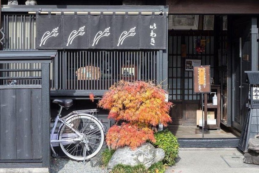 A traditional Japanese building with a bicycle parked in front, surrounded by autumn foliage. 4