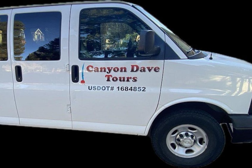 Ein weißer Van mit dem Schriftzug 'Canyon Dave Tours' und einer USDOT-Nummer an der Seite. 3