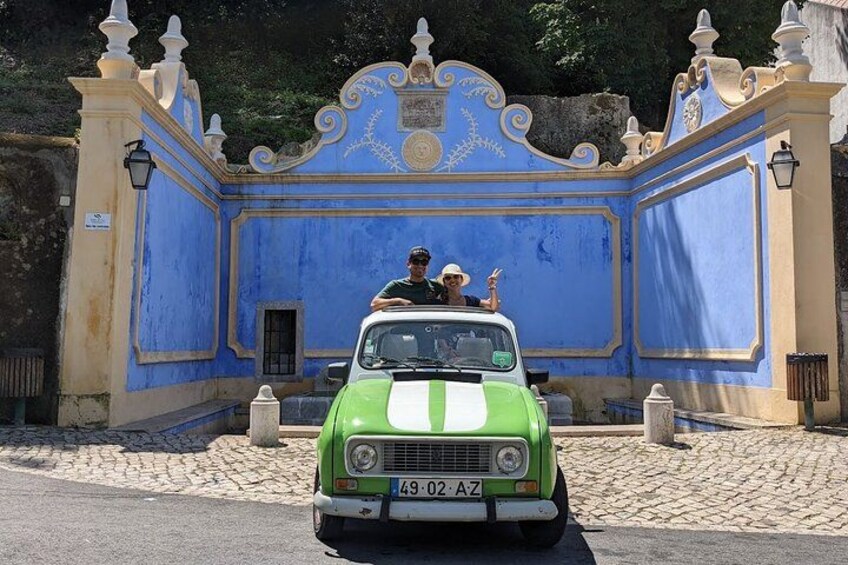 A vintage green car parked in front of a blue and yellow ornate building. 4
