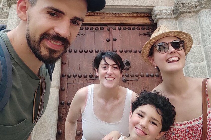 Una familia frente a una puerta de madera con un diseño metálico decorativo. 2